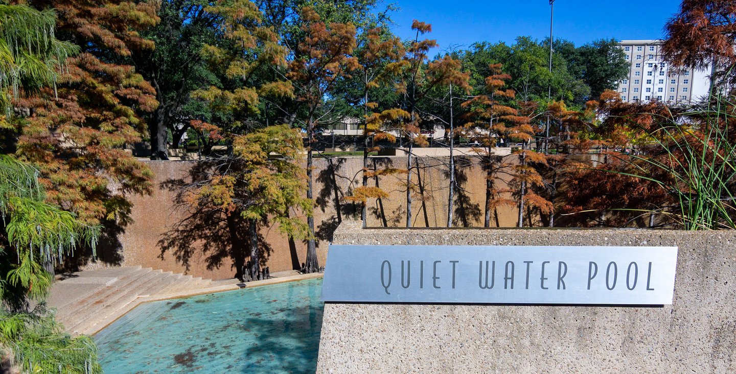 A serene water pool surrounded by lush trees, featuring a sign that reads "Quiet Water Pool." The setting invites relaxation and tranquility.