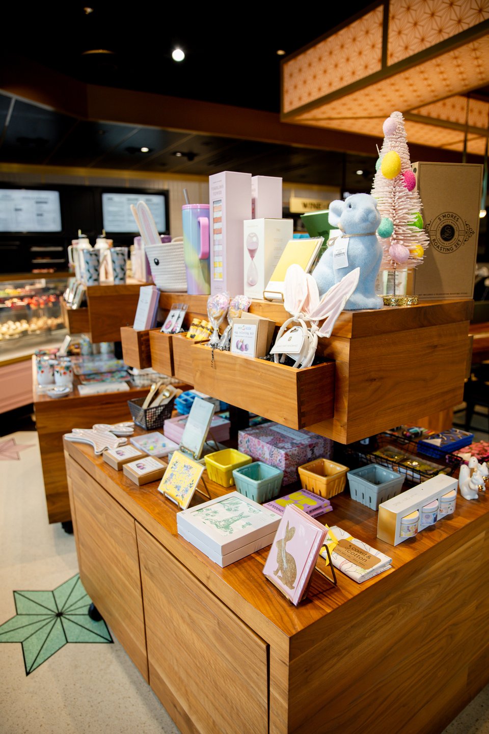 Colorful display of assorted gifts and treats on wooden shelves in a cozy shop, featuring playful decorations and various packaged items.