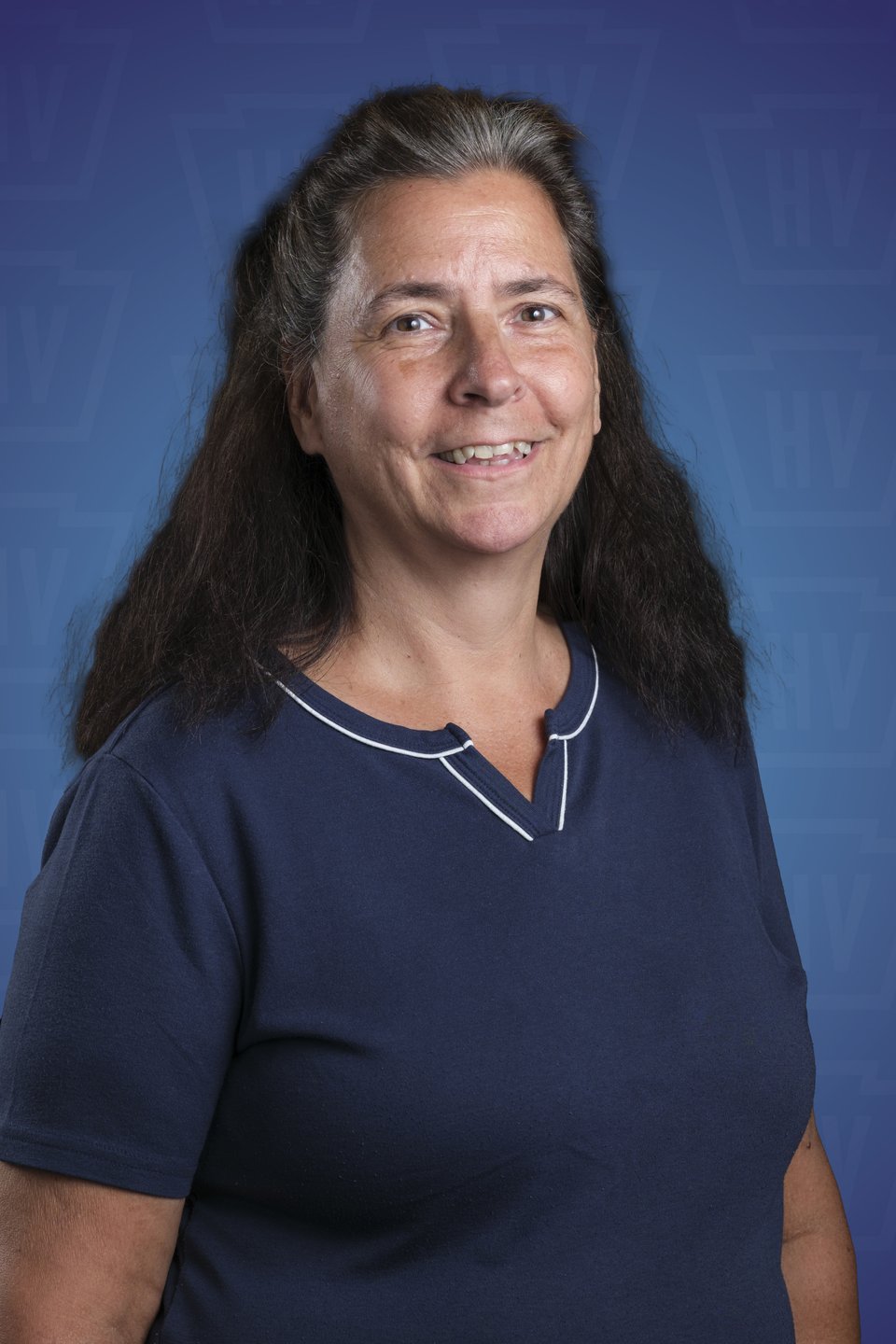 A woman with long dark hair smiles, wearing a navy blue shirt with a white collar. The background features a subtle blue gradient.