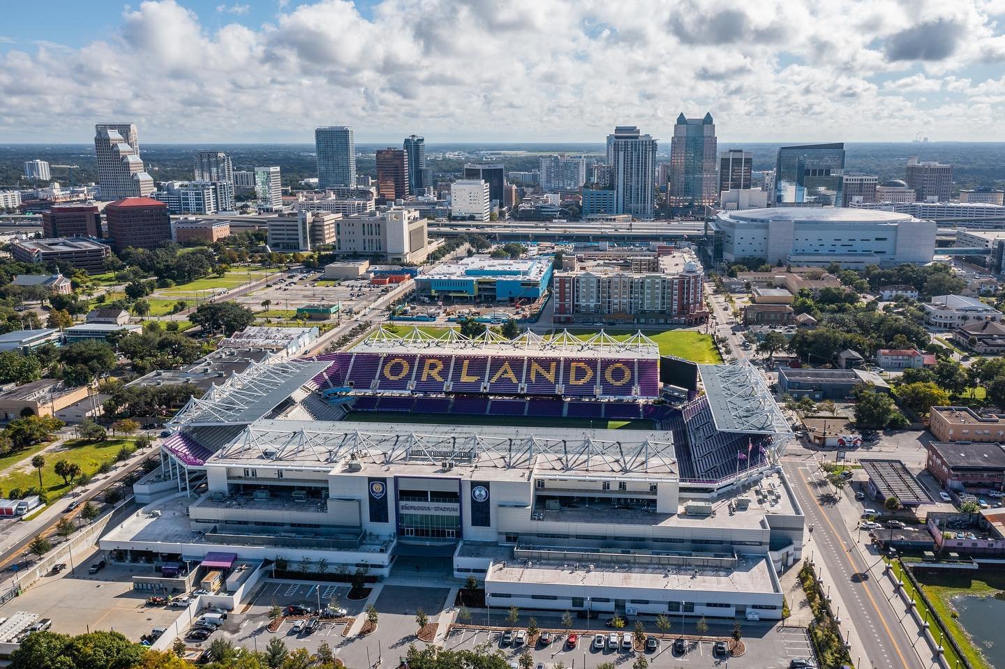 Aerial view of Orlando's downtown skyline featuring the Exploria Stadium, surrounded by urban parks and city buildings.