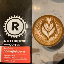 A coffee bag labeled "Rothrock Coffee" with a logo on the left, and a latte art heart design in a circular cup on the right.