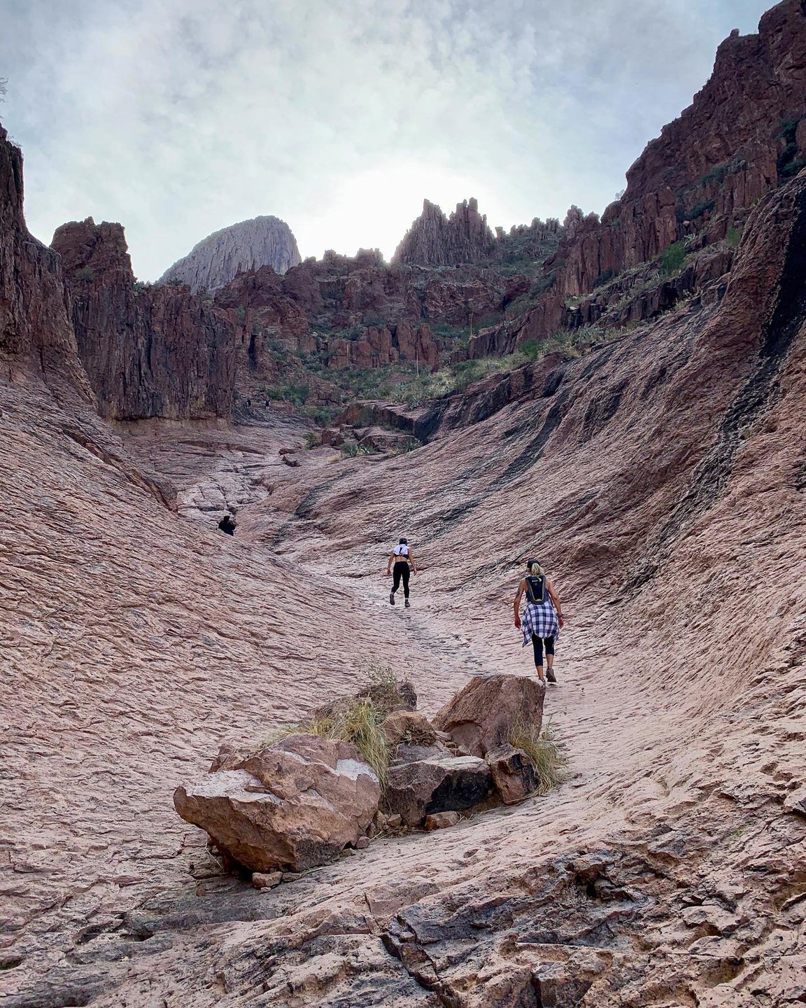 Photo by user demdirtymountaingirls, caption reads The Iron Throne of the Supes. 🙌 Thankfully, unlike the fictional Iron Throne, everyone shares this magical iron & has fun there & makes all the happy faces about it! 👏🧡
.
.
#letgojonsnow #magicalplaces  #flatiron #siphondrawtrail #superstitionmountains #lovethesupes  #dirtymountaingirls #girlgang #hikearizona #hikeaz #arizona #instagramaz #hikeaztrails #arizonahikersguide #lifeofadventure #westbysouthwest #igsouthwest #keepexploring #hikelife #adventureon #explorearizona #exploreaz #aztrails #arizonalife #arizonaisgorgeous #arizonahiking #explore #leavenotrace #optoutside #getoutstayout