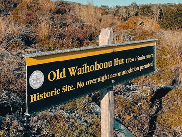 Sign for Old Waihohonu Hut, indicating a 170m walk with a 5-minute return. Highlights its historic significance and no overnight stay policy.