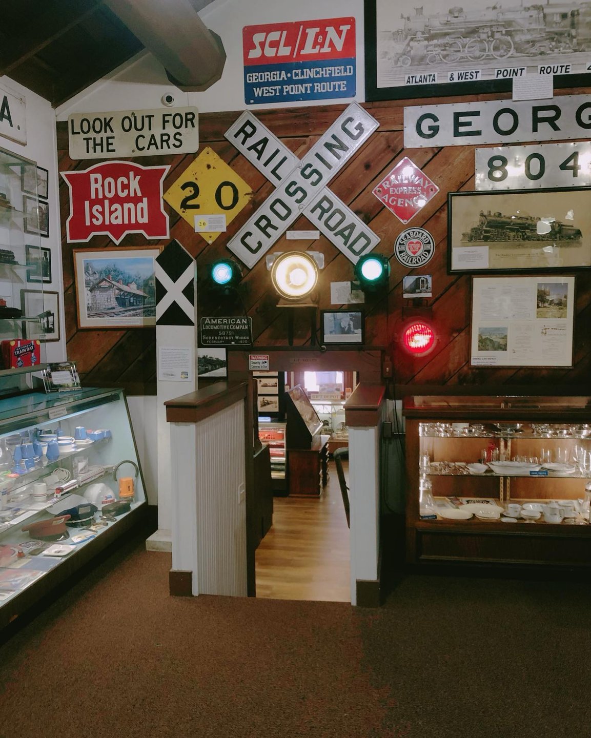 Interior view of a museum showcasing vintage railroad signs and artifacts. Displays include glass cases with memorabilia and illuminated signals.