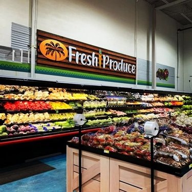 Colorful display of fresh produce in a grocery store, featuring a variety of fruits and vegetables under a "Fresh Produce" sign.